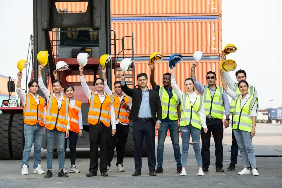 Logistics Team hired by logistics recruitment agency celebrating at a busy shipping yard.