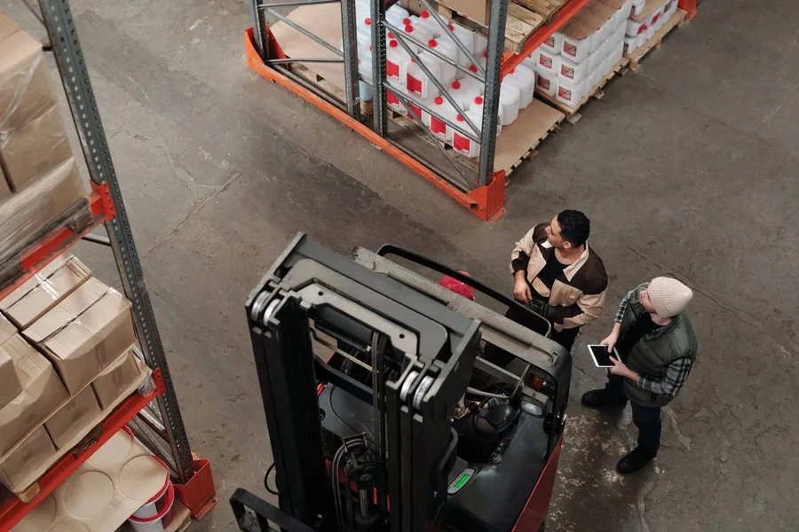 Warehouse employees discussing logistics near a forklift