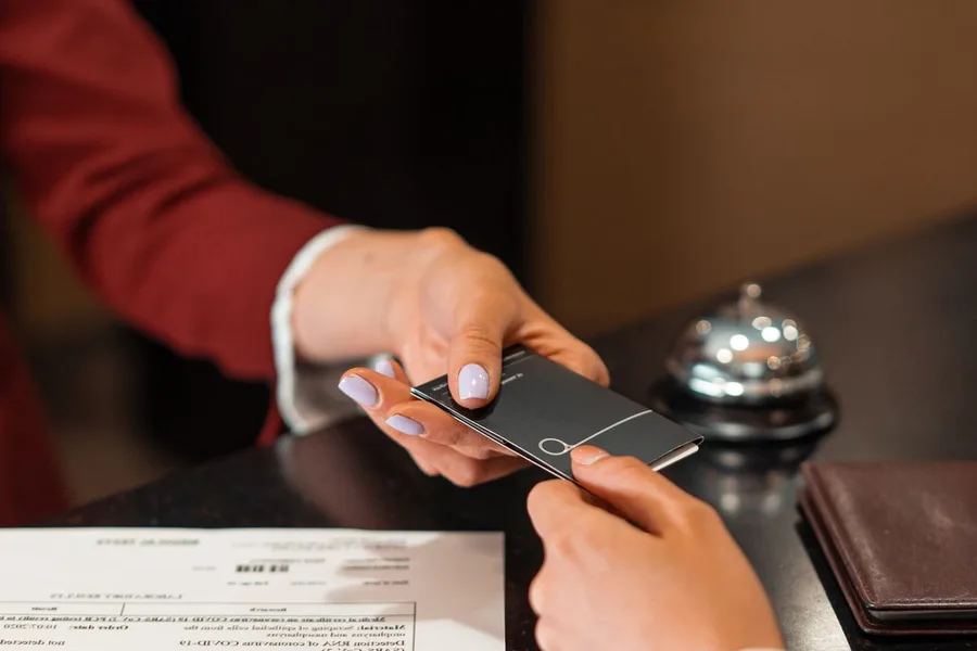 Hotel receptionist handing a key card to a guest