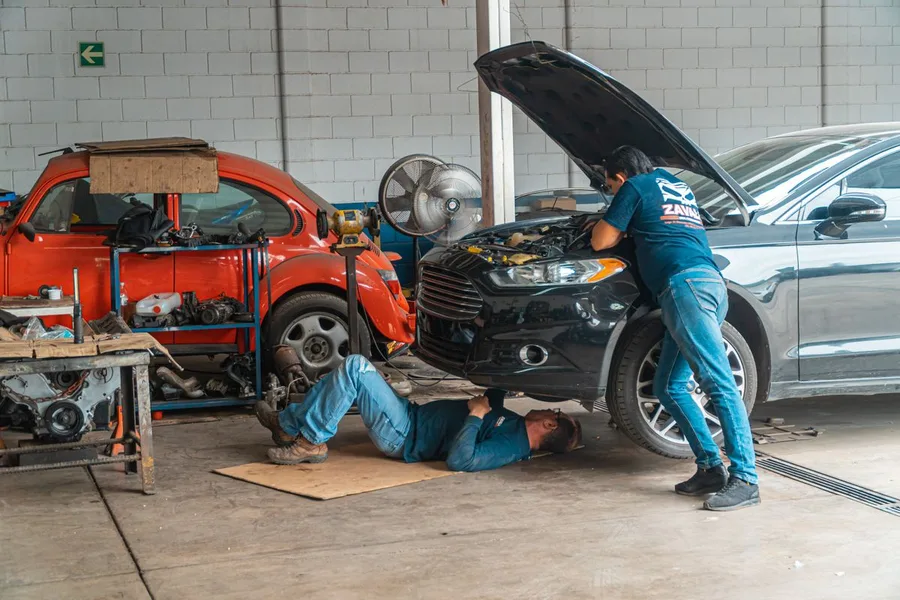 Automotive mechanics repairing cars in a professional workshop